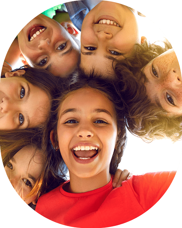 Bunch of cheerful joyful cute little children playing together and having fun. Group portrait of happy kids huddling, looking down at camera and smiling. Low angle, view from below. Friendship concept